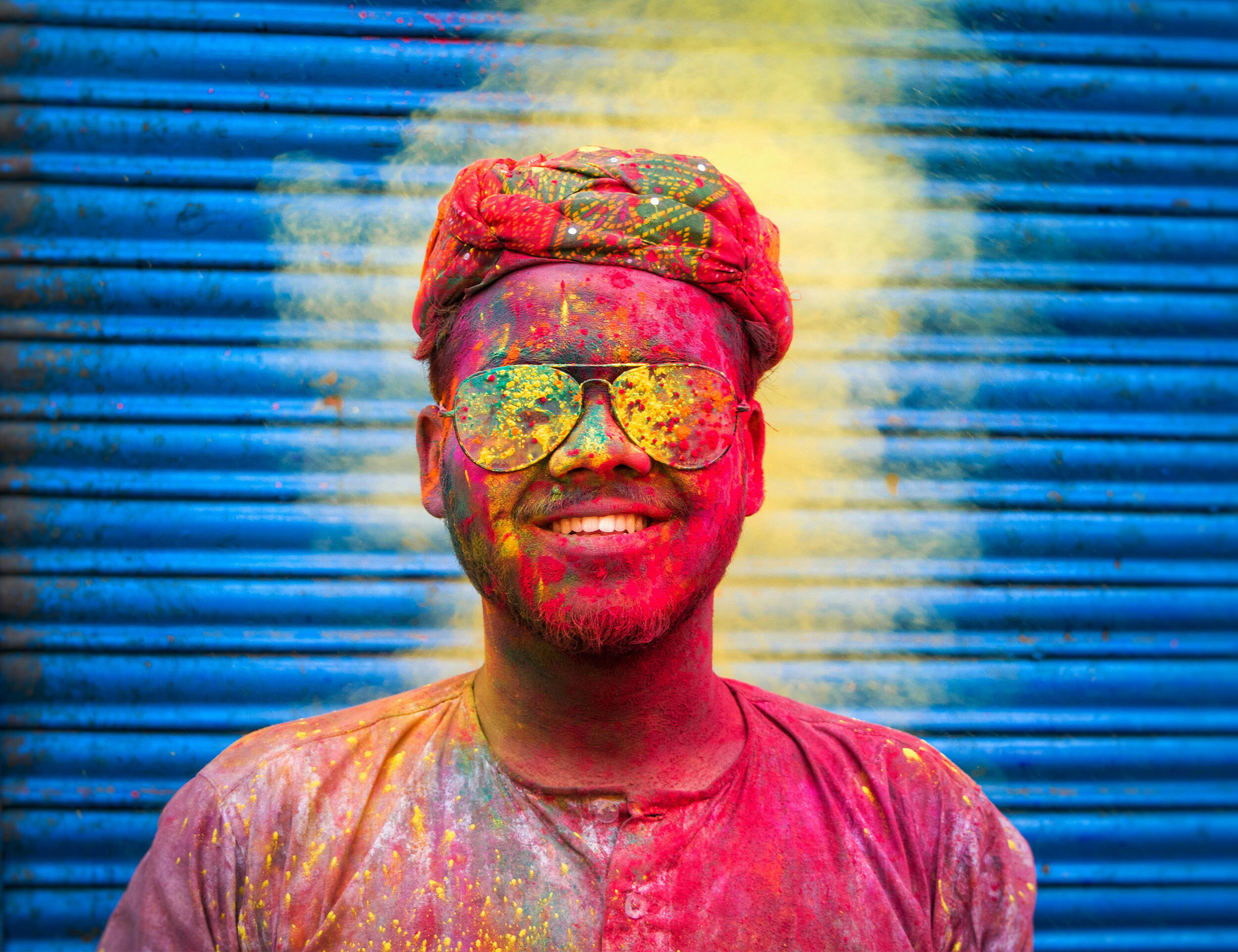 A man wearing sunglasses and smiling with colour on his face  